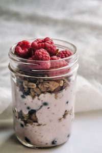 Creamy raspberry yogurt overnight oats topped with nuts and berries, perfect for a healthy breakfast or snack.