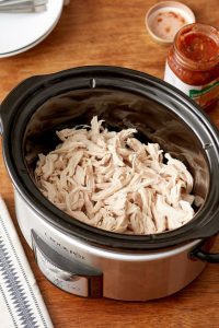  A slow cooker filled with boiled chicken, ready to be used as a filling for sweet potatoes, showcasing a hearty meal preparation.