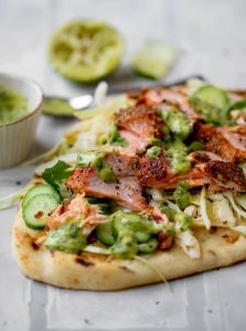 Ready-to-serve grilled BBQ salmon flatbread garnished with cucumber slices and lime, perfect for a delightful meal.